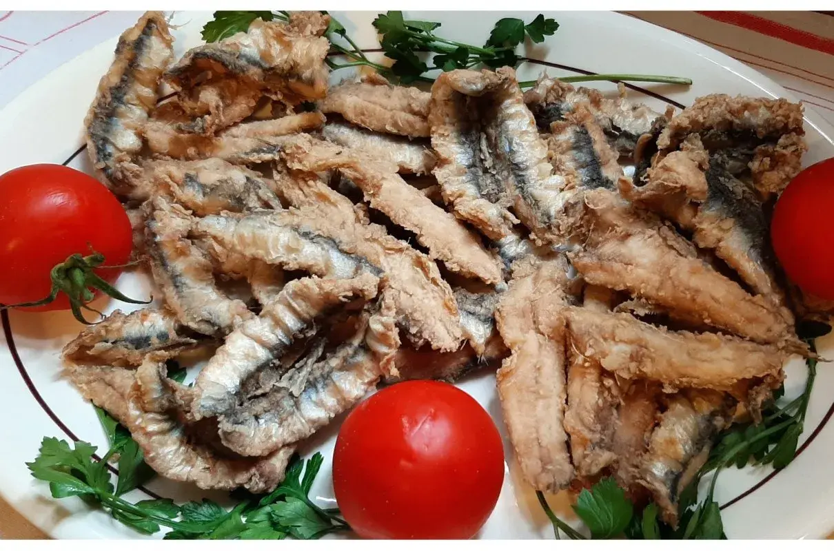 Chrupiące filet anchois z sardeli, podane z pomidorami i natką pietruszki. Pyszna przekąska.