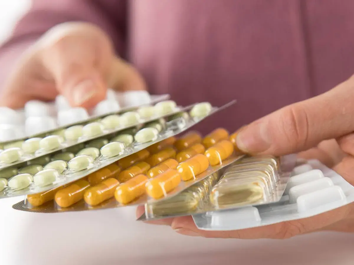 Hände halten mehrere Blisterpackungen mit Tabletten und Kapseln. Die Frage, darf man Tabletten mit ins Flugzeug nehmen, wird hier visuell thematisiert.