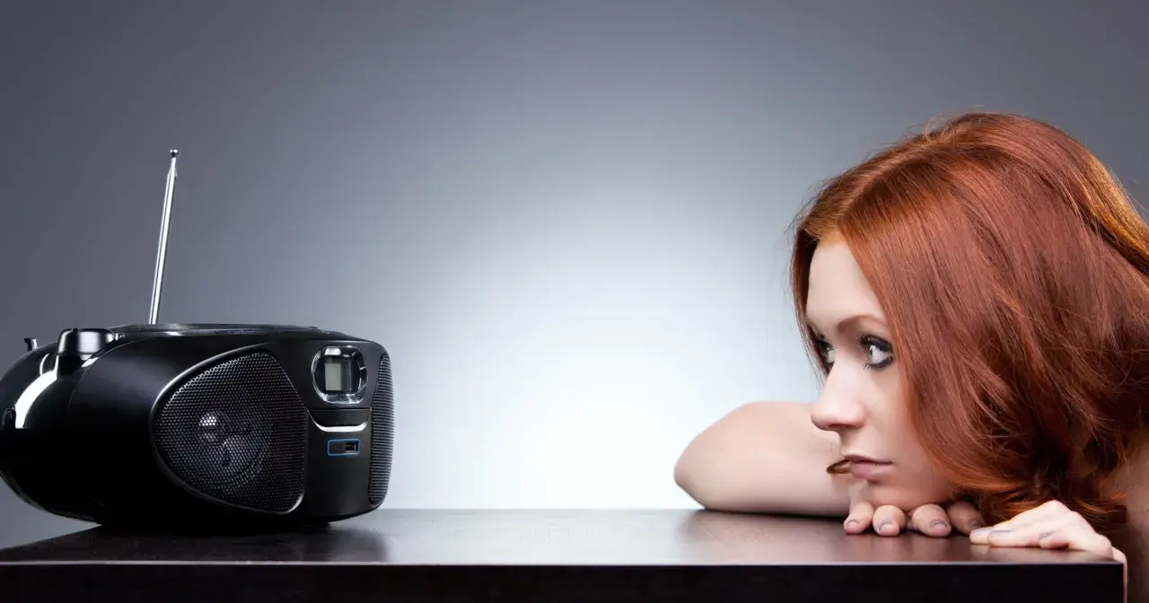 Rudowłosa dziewczyna wsłuchuje się w radio. Może właśnie słyszy ulubioną piosenkę z Vox FM Warszawa.