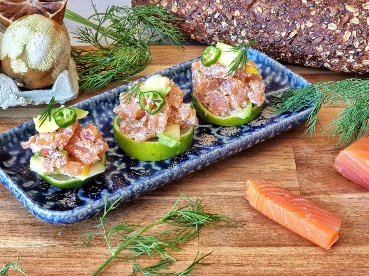 Tartar de salmón fresco servido en mitades de lima, adornado con aguacate y jalapeño.