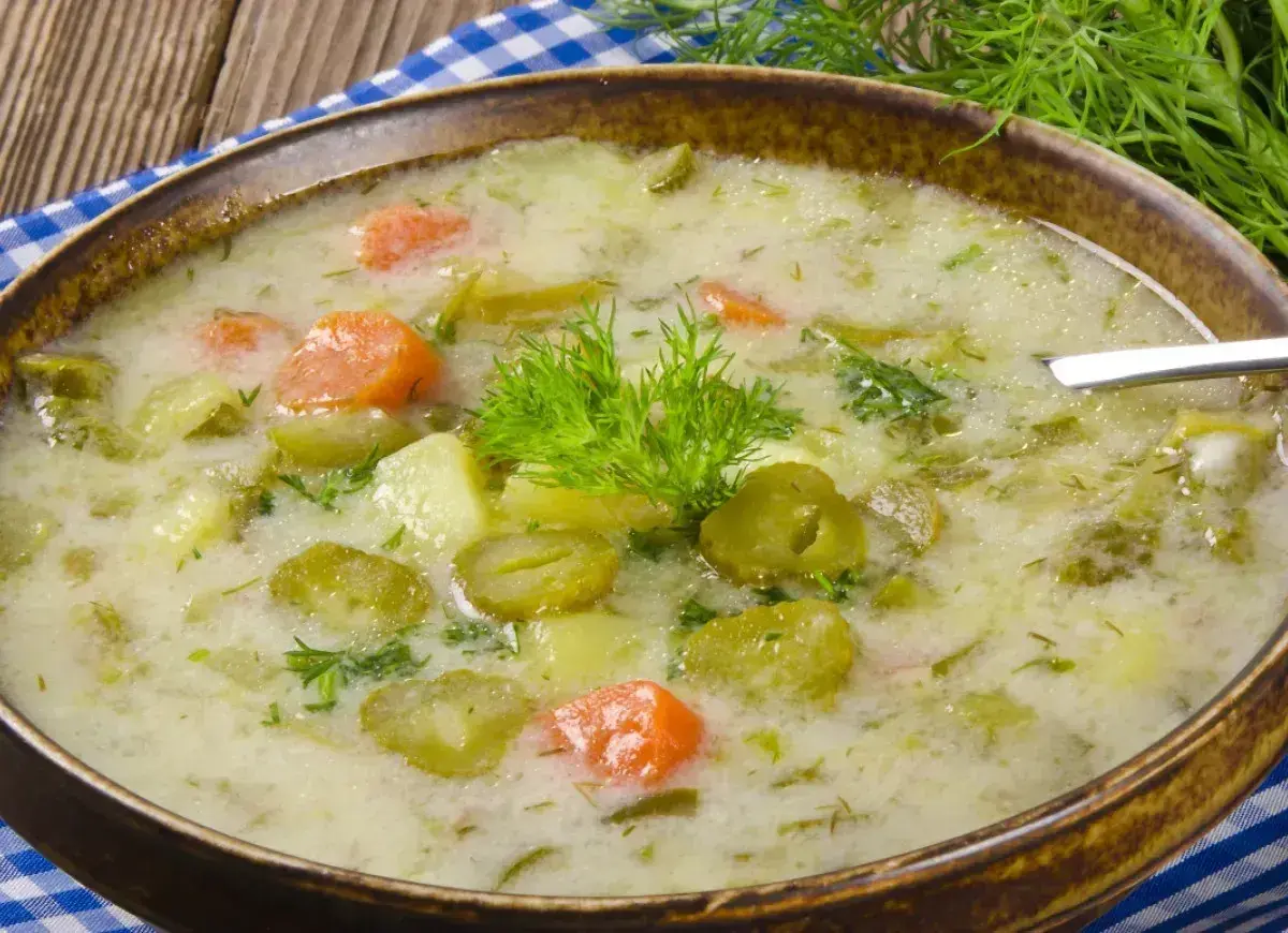 Zupa ogórkowa z ziemniakami i marchewką, ozdobiona koperkiem. Pamiętaj, jakiej przyprawy nie wolno dodawać do zupy ogórkowej, by nie zepsuć jej smaku!