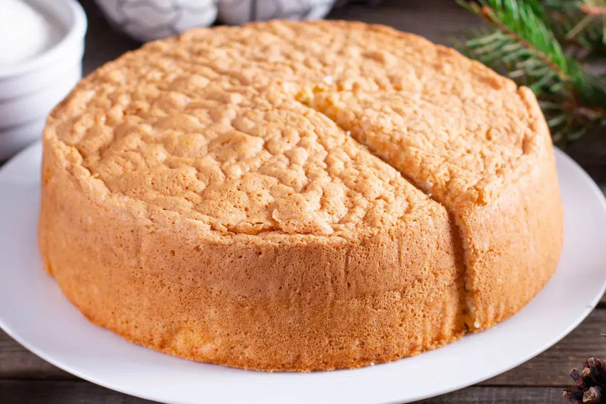 Un soffice angel cake altissima, pronto per essere decorato. La sua consistenza ariosa promette un sapore leggero e delizioso.
