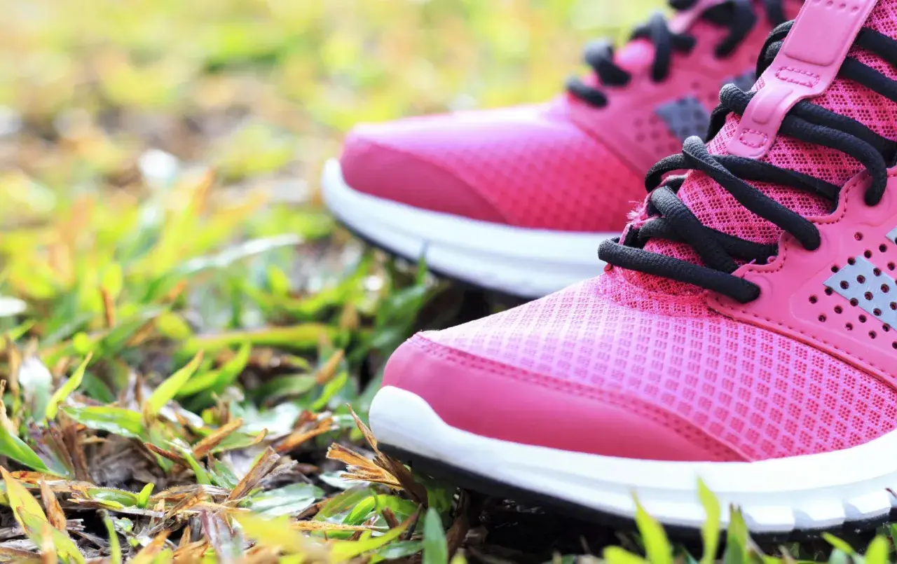 Rosa Laufschuhe mit schwarzen Schnürsenkeln auf Gras. Die richtige Wahl für welche Schuhe bei Kniearthrose?