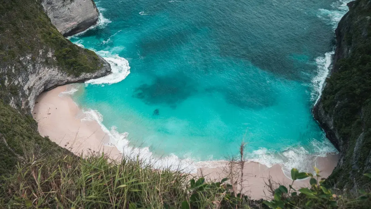 Widok z góry na plażę Kelingking na Nusa Penida z turkusową wodą i klifami.