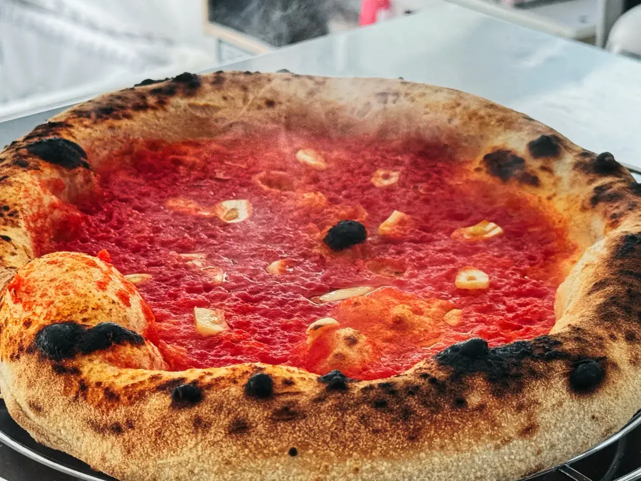 Eine dampfende Pizza Marinara mit knusprigem Rand und roten Tomaten.