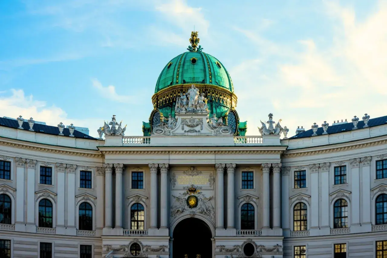 Prunkvolle Kuppel des Hofburg-Palastes in Wien, ein absolutes Wien must see. Majestätische Architektur unter blauem Himmel.