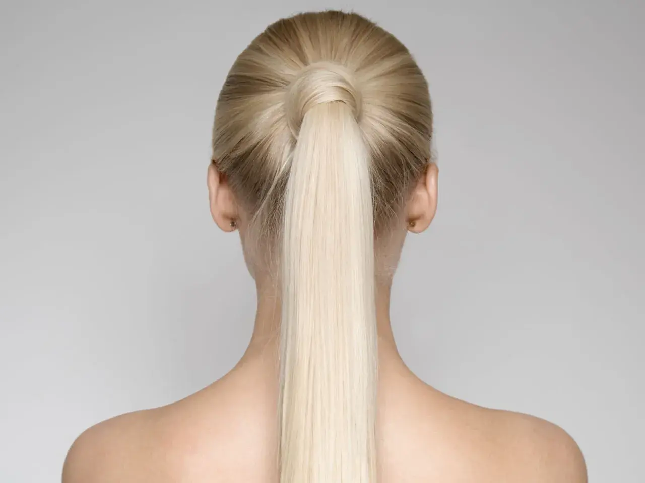 Vista posteriore di una donna con una perfetta coda di cavallo alta bionda, liscia e lucida.