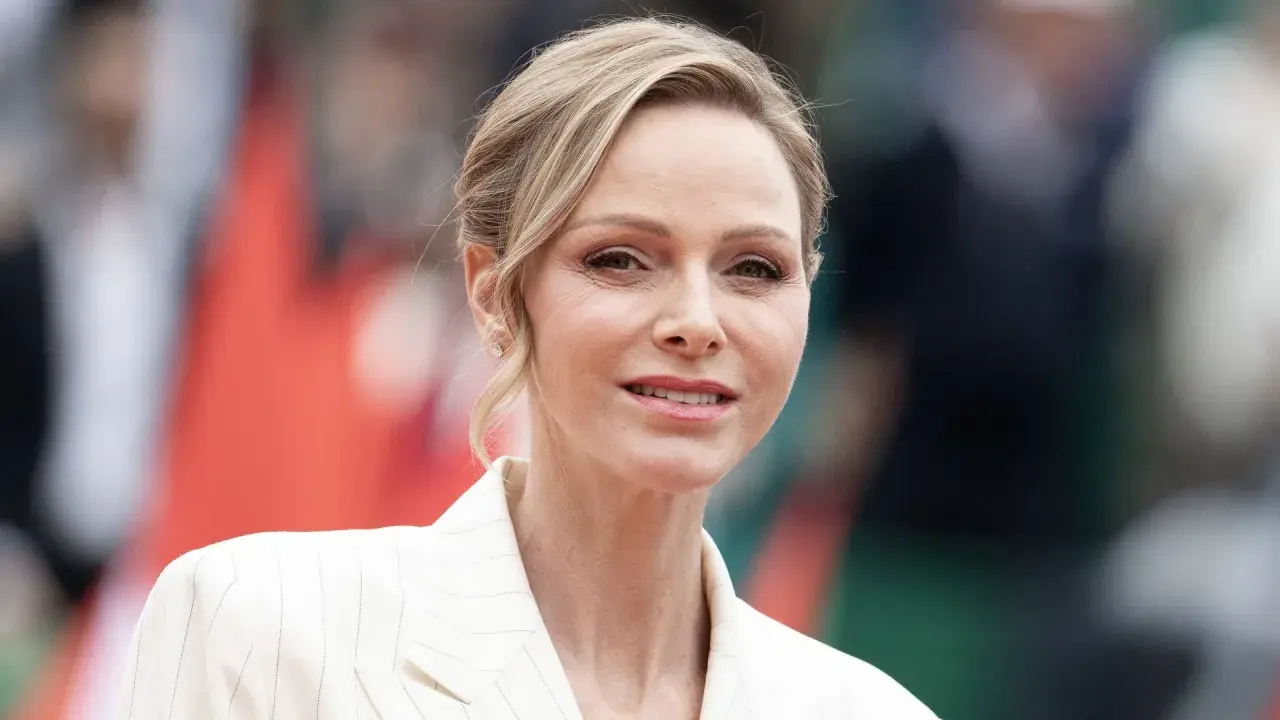 La princesa de Mónaco, Charlene Wittstock, sonríe con un traje blanco a rayas.