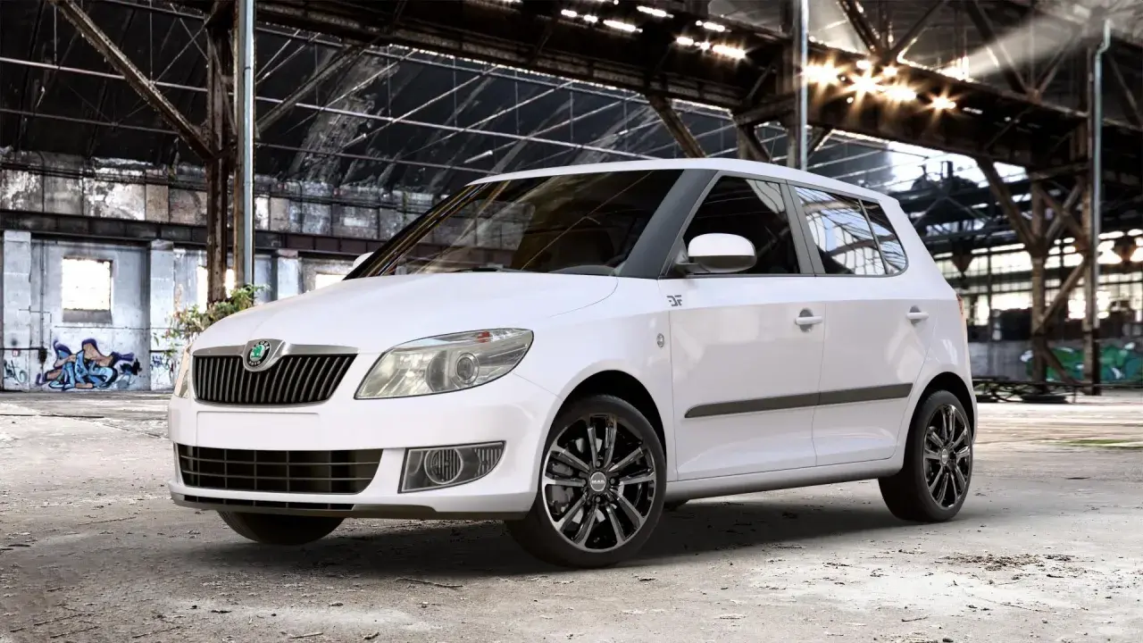 Biała Skoda Fabia z czarnymi felgami stoi w opuszczonej hali. Rozmiar opon idealnie pasuje do sportowego charakteru auta.
