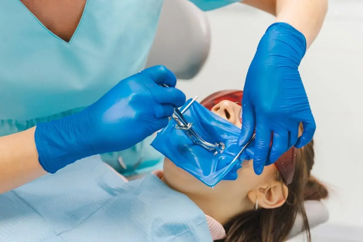 Dentysta zakłada koferdam, izolując pole zabiegowe.