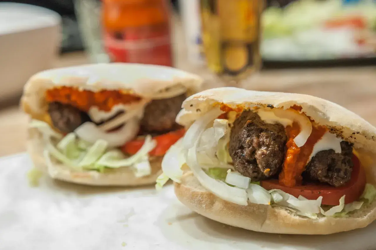 Två saftiga cevapcici i pitabröd med lök, tomat och sås. Perfekt för en snabb och god måltid, som ett enkelt cevapcici recept.