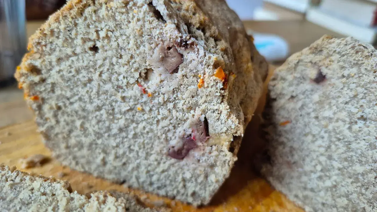 Rebanada de pan sin gluten con trozos de frutos secos y un toque anaranjado.