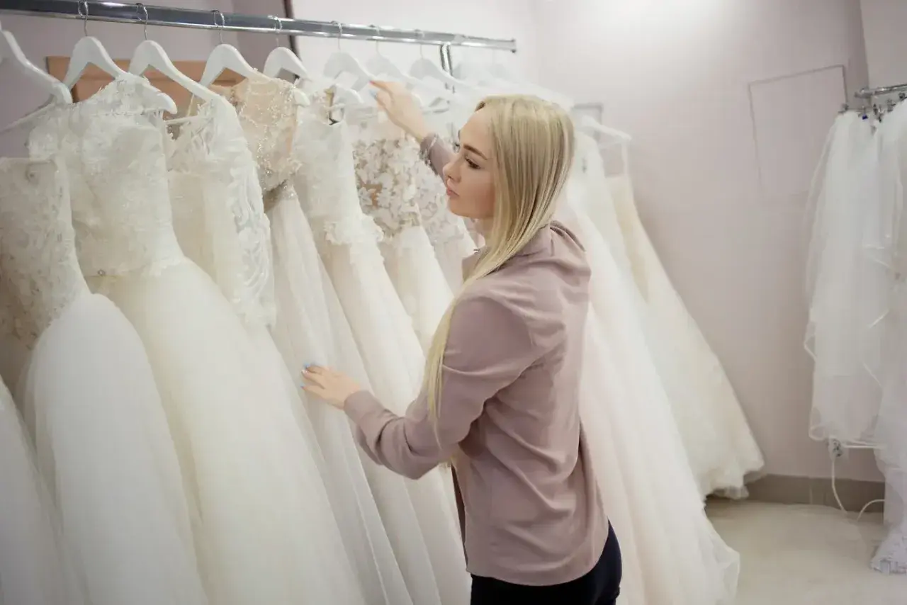 Blondynka wybiera suknię ślubną w salonie sukien ślubnych.