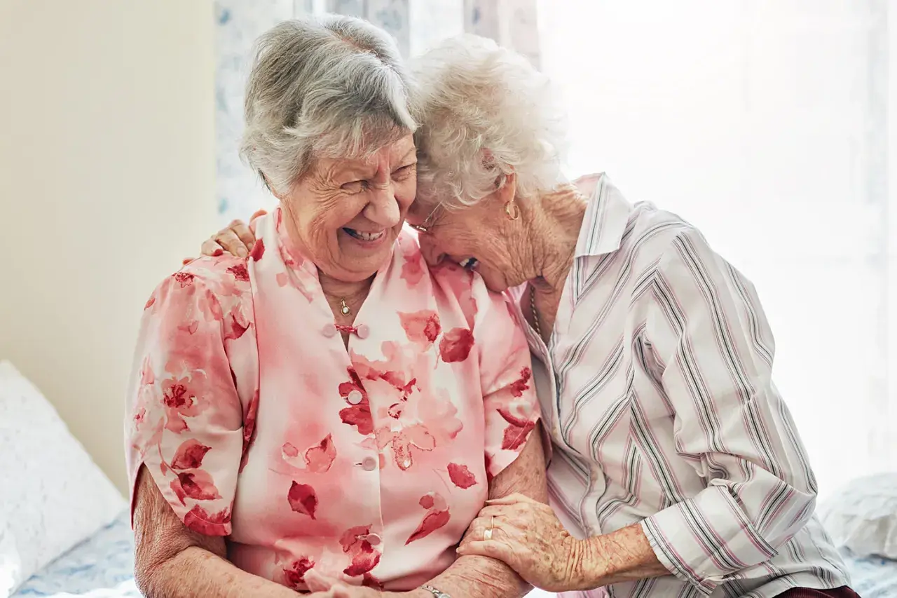 Zwei lachende Seniorinnen, die sich umarmen. Ein schönes Beispiel, wie man neue Freunde finden ab 60 kann.