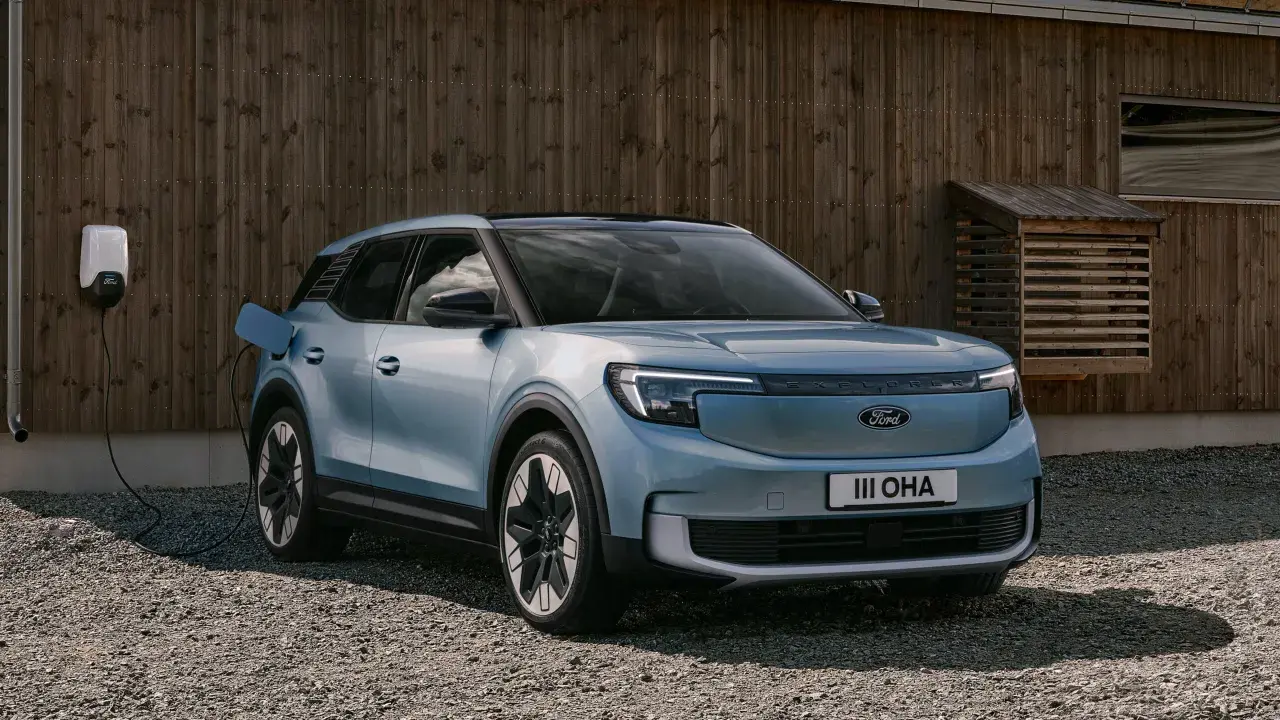 Blå elbil, en Ford Explorer, laddas vid en laddbox framför ett trähus. En spännande ford explorer test.