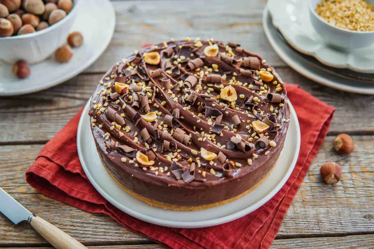 Delizioso cheesecake alla nutella, ricoperto di riccioli di cioccolato e nocciole tostate.