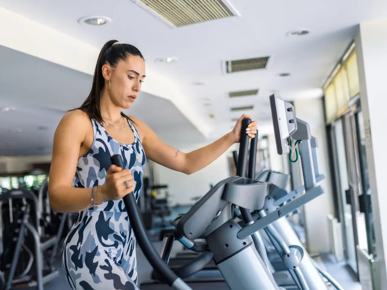 Frau trainiert auf einem Crosstrainer, um ihren Kalorienverbrauch zu steigern.