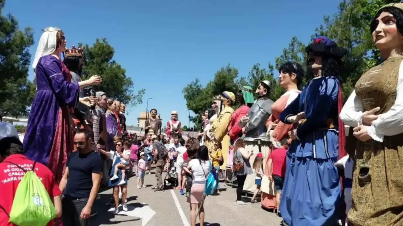 Gigantes y cabezudos desfilan en las fiestas del Parque Goya. Niños y adultos disfrutan de la colorida procesión bajo el sol.