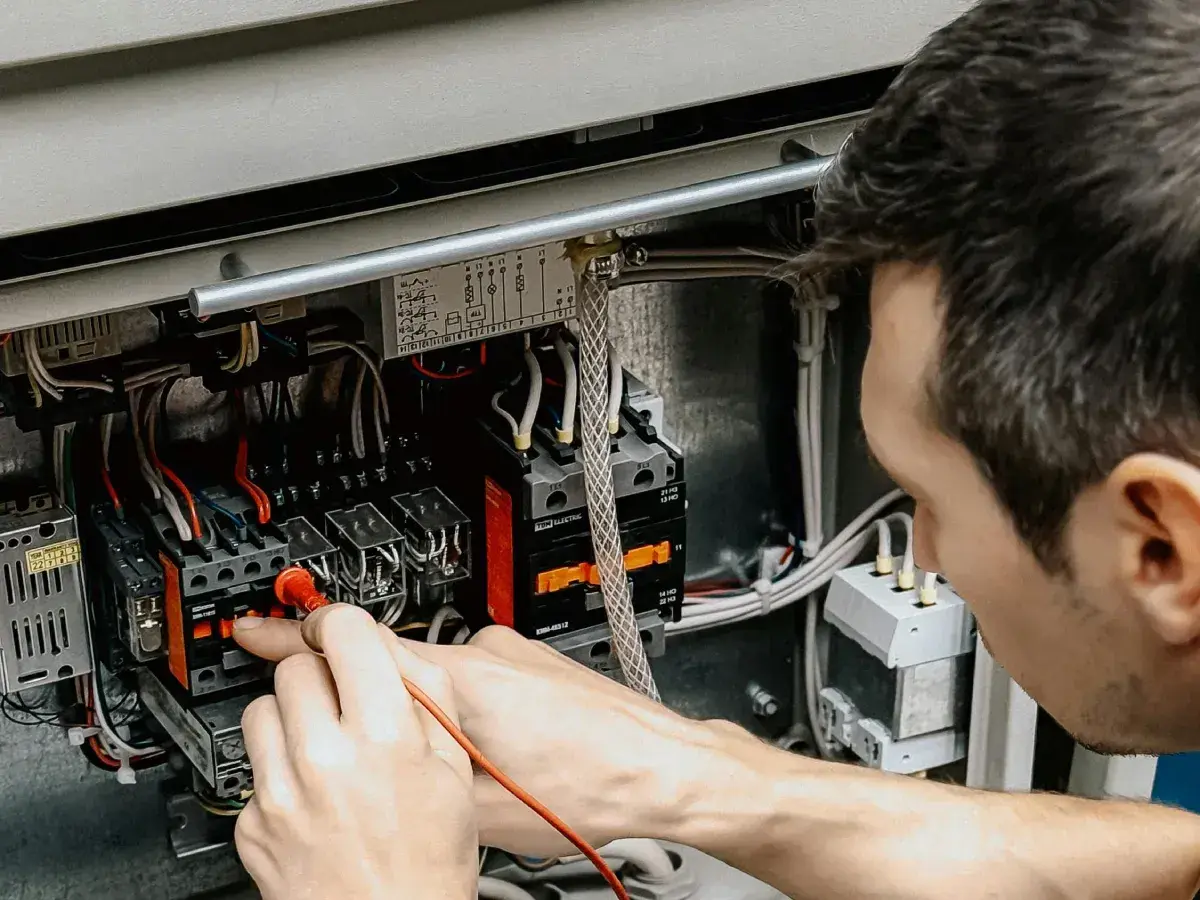 Elektryk mierzy napięcie w skrzynce z bezpiecznikami i przekaźnikami.
