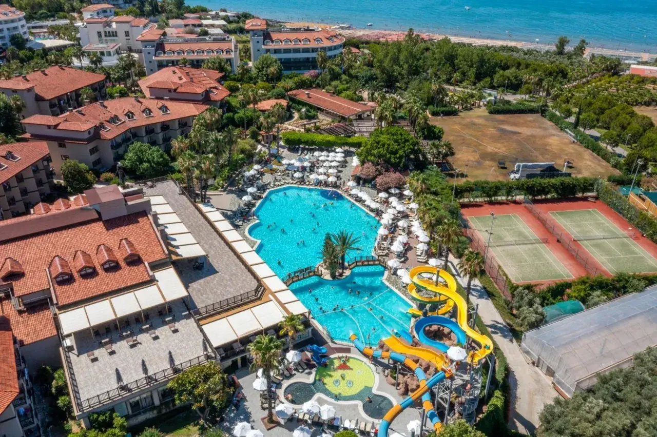 Widok z lotu ptaka na Alba Resort Hotel z basenami, zjeżdżalniami wodnymi, kortami tenisowymi i plażą w tle.