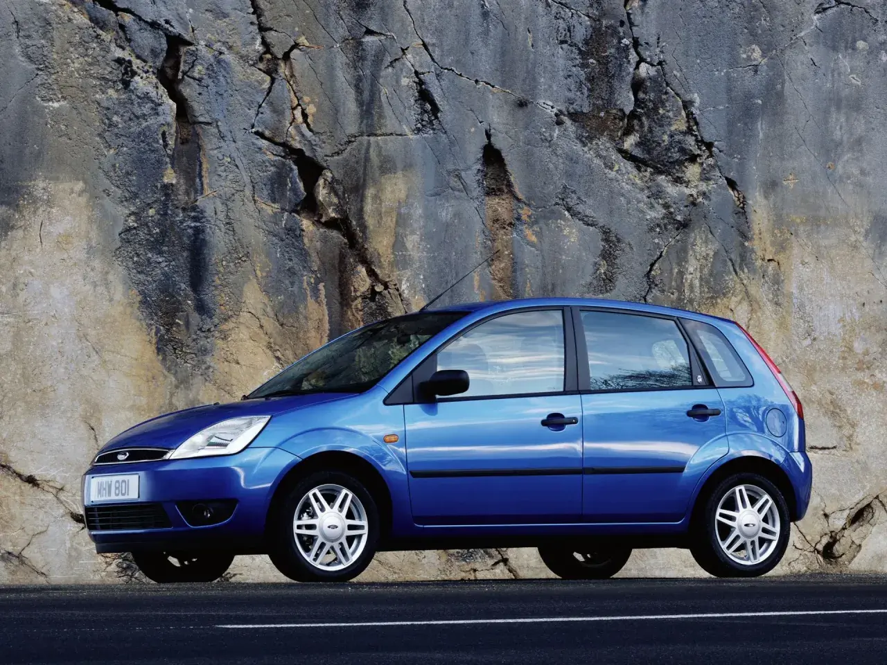 Niebieski Ford Fiesta 2005 zaparkowany przy skalnej ścianie.