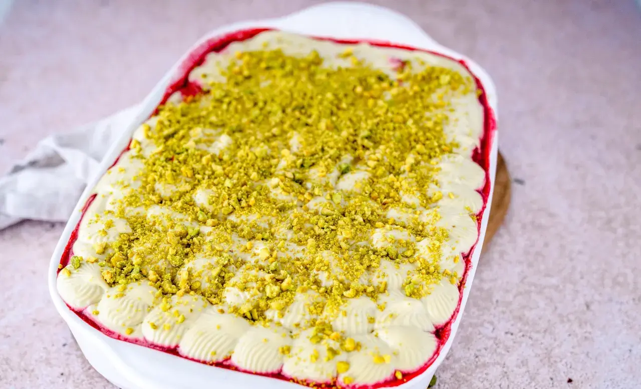 Ein cremiges Pistazien Tiramisu in einer weißen Auflaufform, bestreut mit gehackten Pistazien.