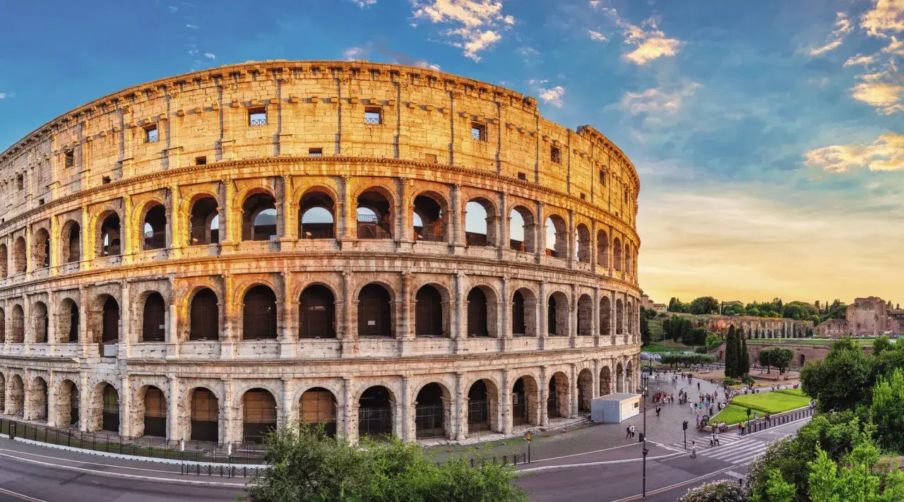 Colosseum i Rom, en ikonisk gammal stad i Italien, badar i gyllene solljus. Turister promenerar på torget framför den imponerande amfiteatern.