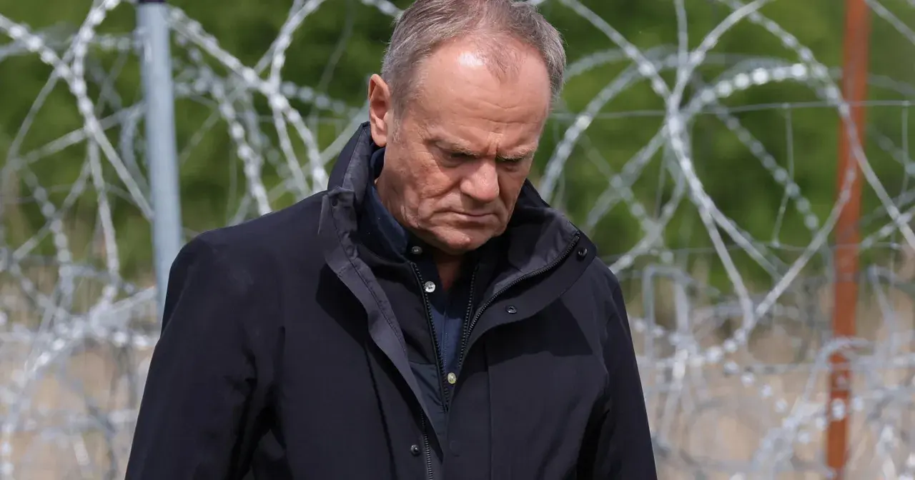 Mężczyzna w ciemnej kurtce patrzy w dół, za nim drut kolczasty. Czy to symbol jego hipokryzji?