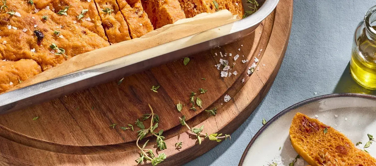 Frisch gebackene focaccia mit tomaten, bestreut mit Meersalz und Thymian, bereit zum Genießen.