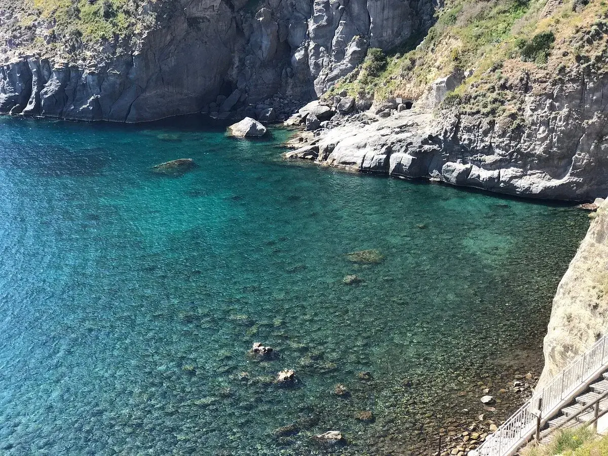Acque cristalline e scogliere a picco a Ischia. Un angolo di paradiso dove la spiaggia incontra l'acqua calda, invitando al relax.