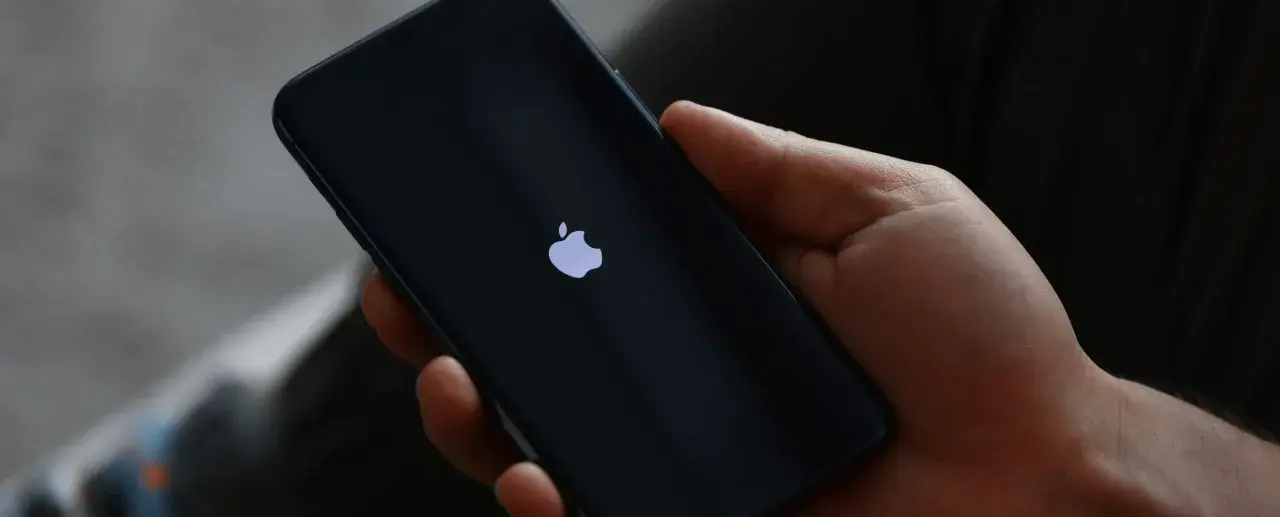 Dłoń trzyma iPhone 13 z logo Apple. Czas na reset? Dowiedz się, jak zresetować iPhone 13.