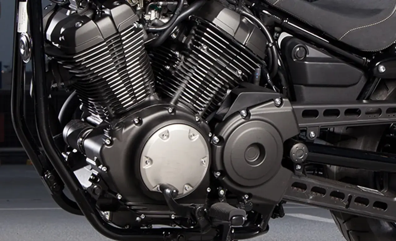 Silnik V-twin motocykla Yamaha XV950, z charakterystycznymi żebrowanymi cylindrami i czarnymi osłonami.