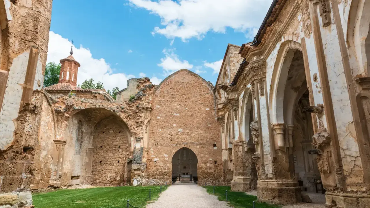 Ruinas de un antiguo convento, lugar donde se rodó Traitors España. El cielo azul con nubes contrasta con la piedra erosionada.