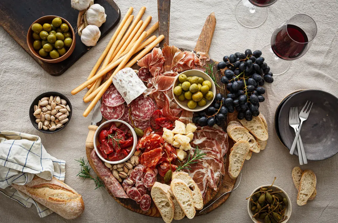 En generös bricka med italienska snacks: charkuterier, oliver, soltorkade tomater, ost, vindruvor, grissini och bröd. Perfekt för en mysig kväll.