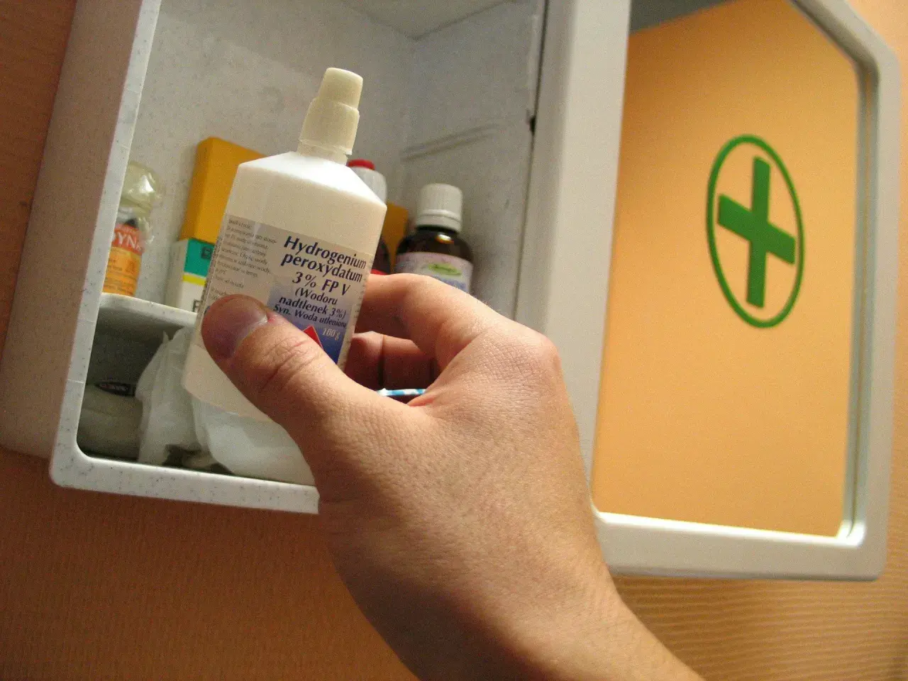Ręka wyjmuje z apteczki butelkę z napisem "Hydrogenium peroxydatum 3% (Wodoru nadtlenek 3%) Syn. Woda utleniona". Idealna do walki z pleśnią.