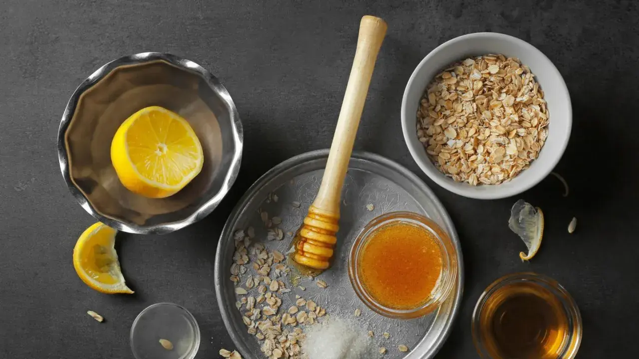 Zutaten für ein natürliches Peeling zur Hautentgiftung: Haferflocken, Honig, Zitrone und Zucker.