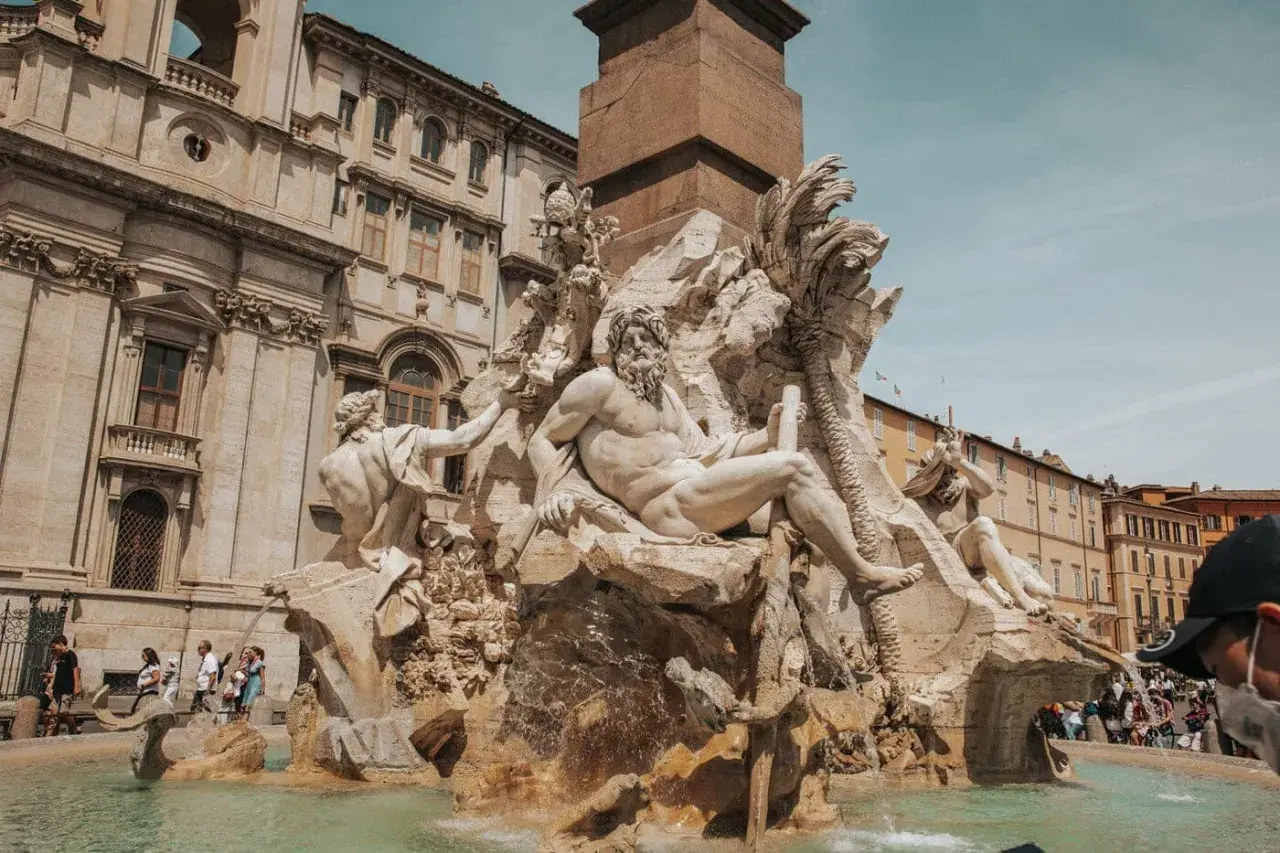 Fontanna Czterech Rzek na Piazza Navona w Rzymie, z majestatycznymi rzeźbami i turystami w tle.