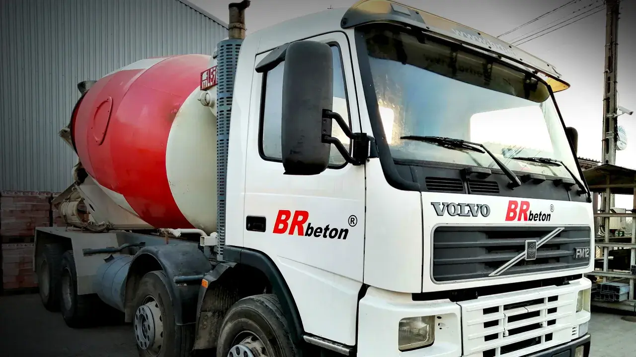 Biała ciężarówka Volvo z czerwoną obrotową beczką na beton. To jeden z rodzajów betoniarek, gotowy do transportu budowlanego.