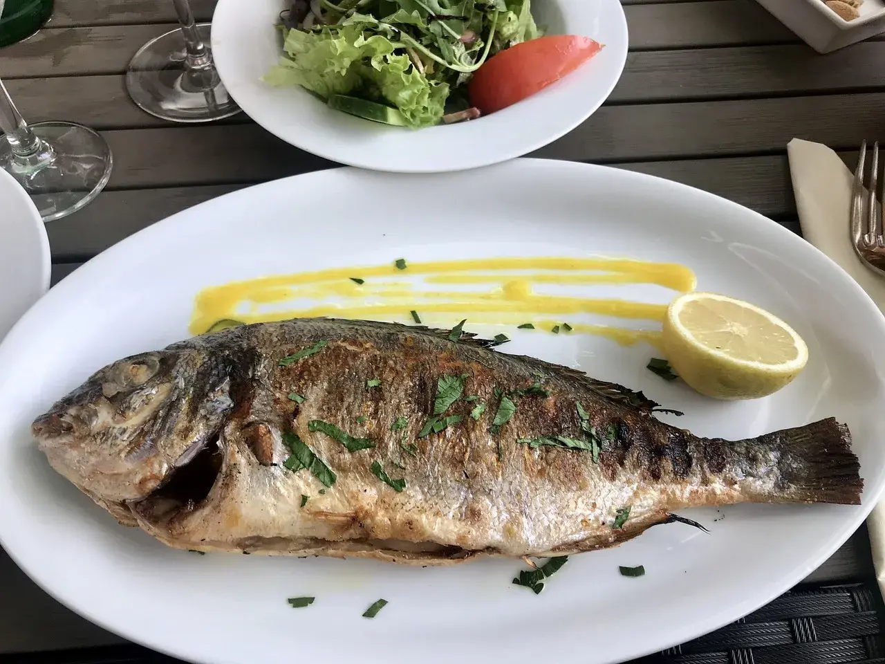 Dorade entière grillée à la plancha, sauce jaune, quartier de citron. Parfait pour le temps de cuisson.