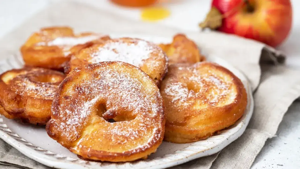 Délicieux beignets aux pommes saupoudrés de sucre glace, prêts à être dégustés.