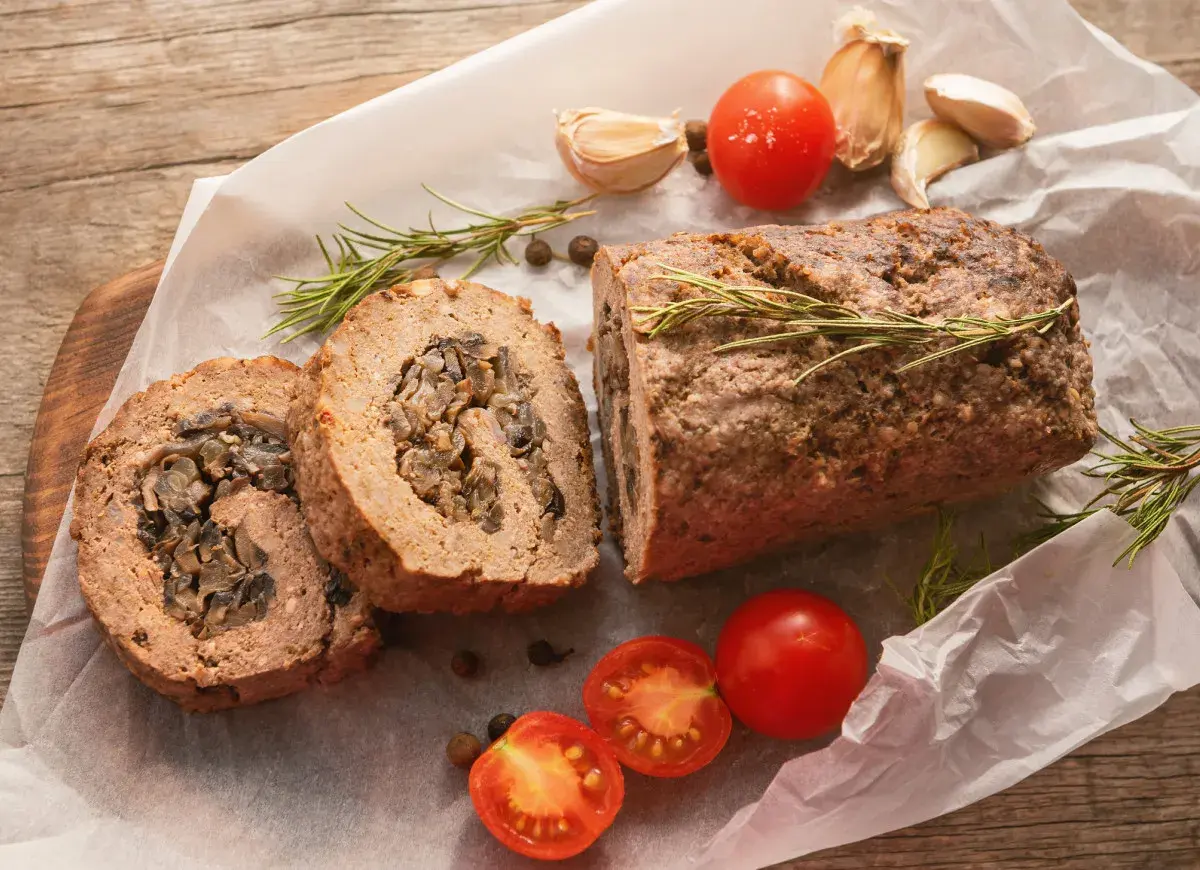 Pyszna rolada z mięsa mielonego z grzybami, podana z pomidorkami i rozmarynem.