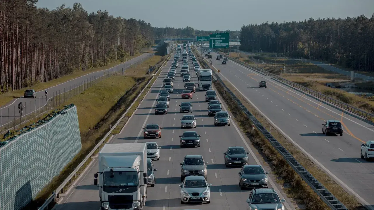 Korek na s2 trasa. Długi sznur samochodów i ciężarówek w drodze do celu, otoczony lasem.