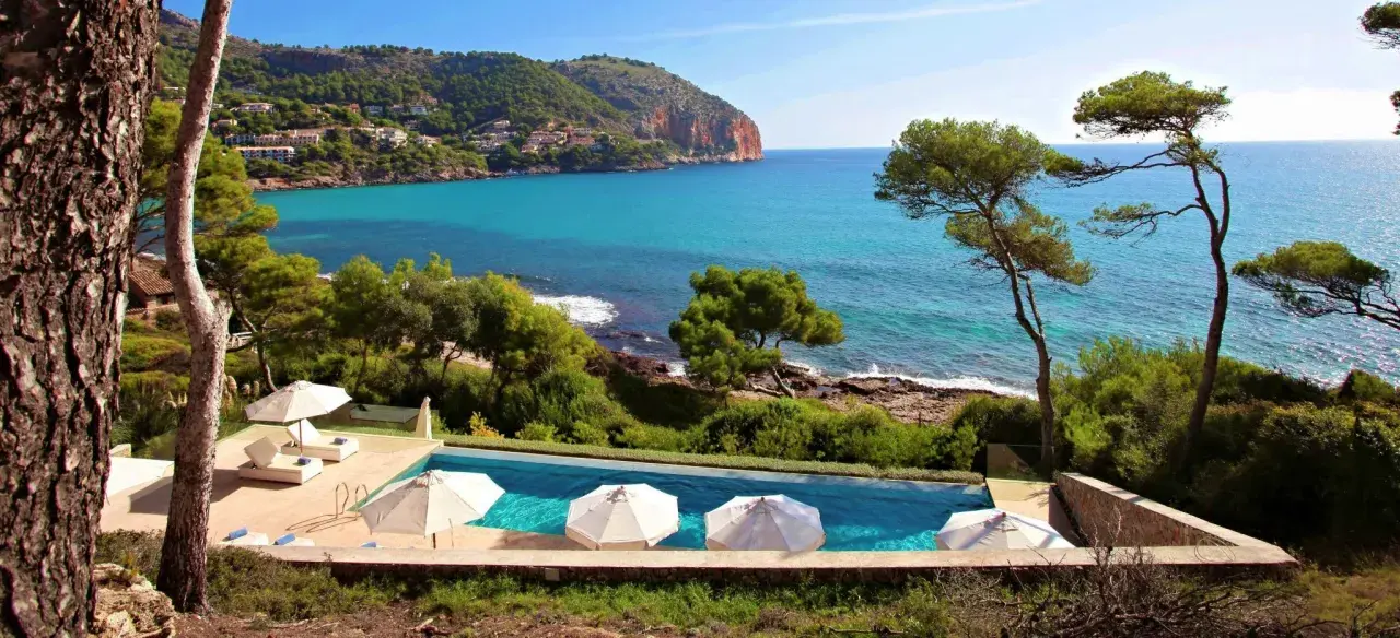 Traumhafter Poolblick auf das Meer bei Simoneta Mallorca. Sonnenschirme und Liegen laden zum Entspannen ein.