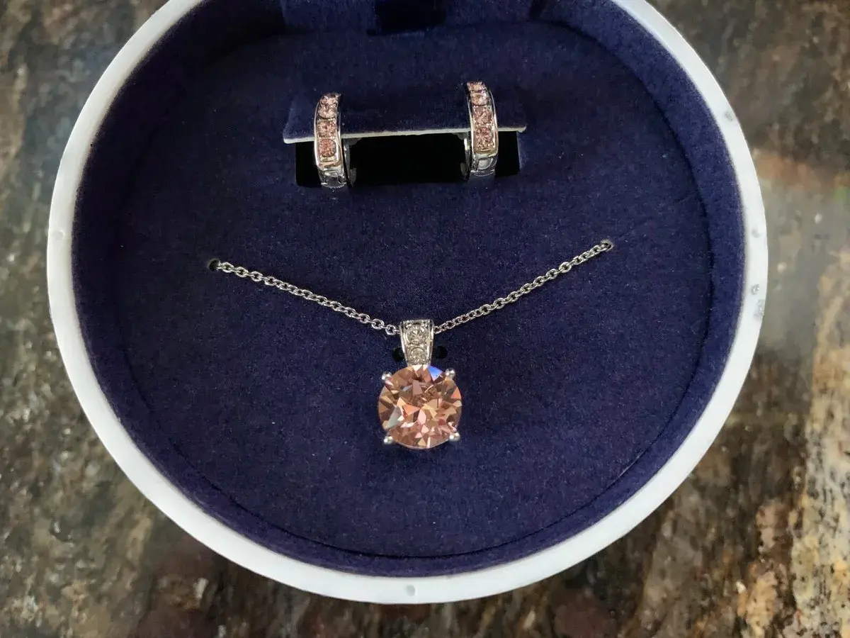 Eleganckie **Swarovski komplety**: naszyjnik z brzoskwiniowym kryształem i kolczyki w pudełku.