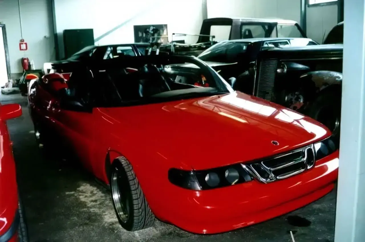 En röd Saab 9000 cabriolet står i ett garage, redo för en tur.