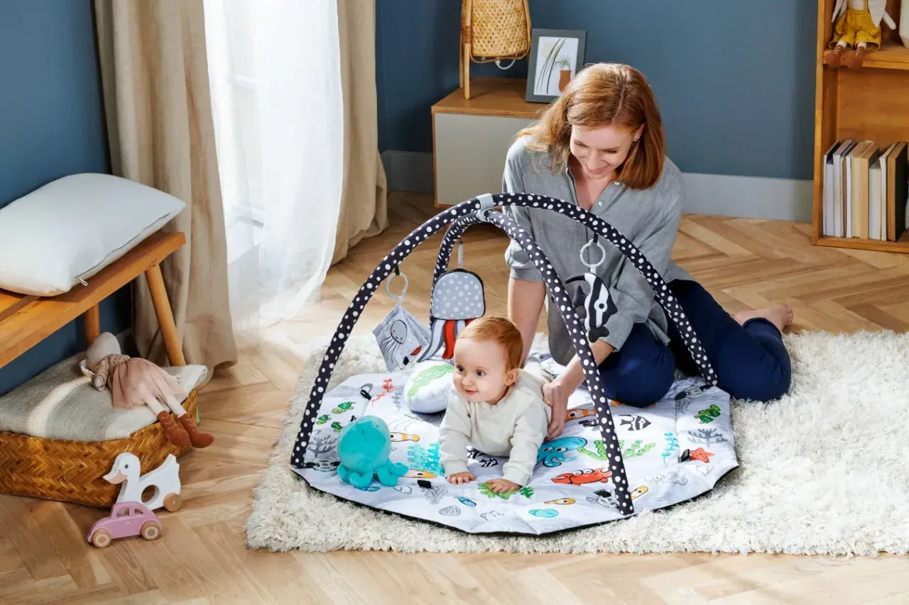 Mama bawi się z niemowlakiem na macie edukacyjnej dla niemowląt od kiedy tylko zacznie raczkować. Kolorowa mata z zabawkami zachęca do odkrywania świata.