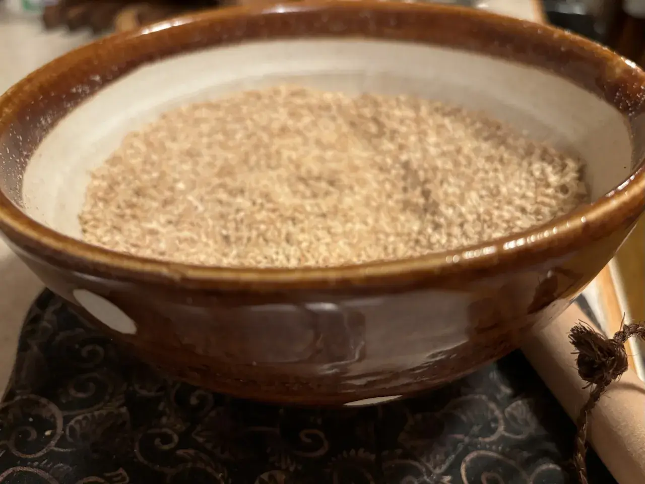 A bowl of gomo shio, a Japanese seasoning, sits on a patterned cloth.
