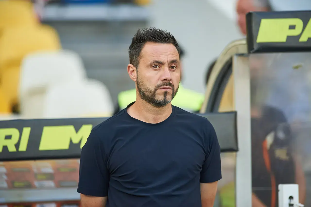 Roberto De Zerbi, mit seinem charakteristischen Blick, steht im Stadion. Seine bisherigen Trainerstationen prägen seine Laufbahn.