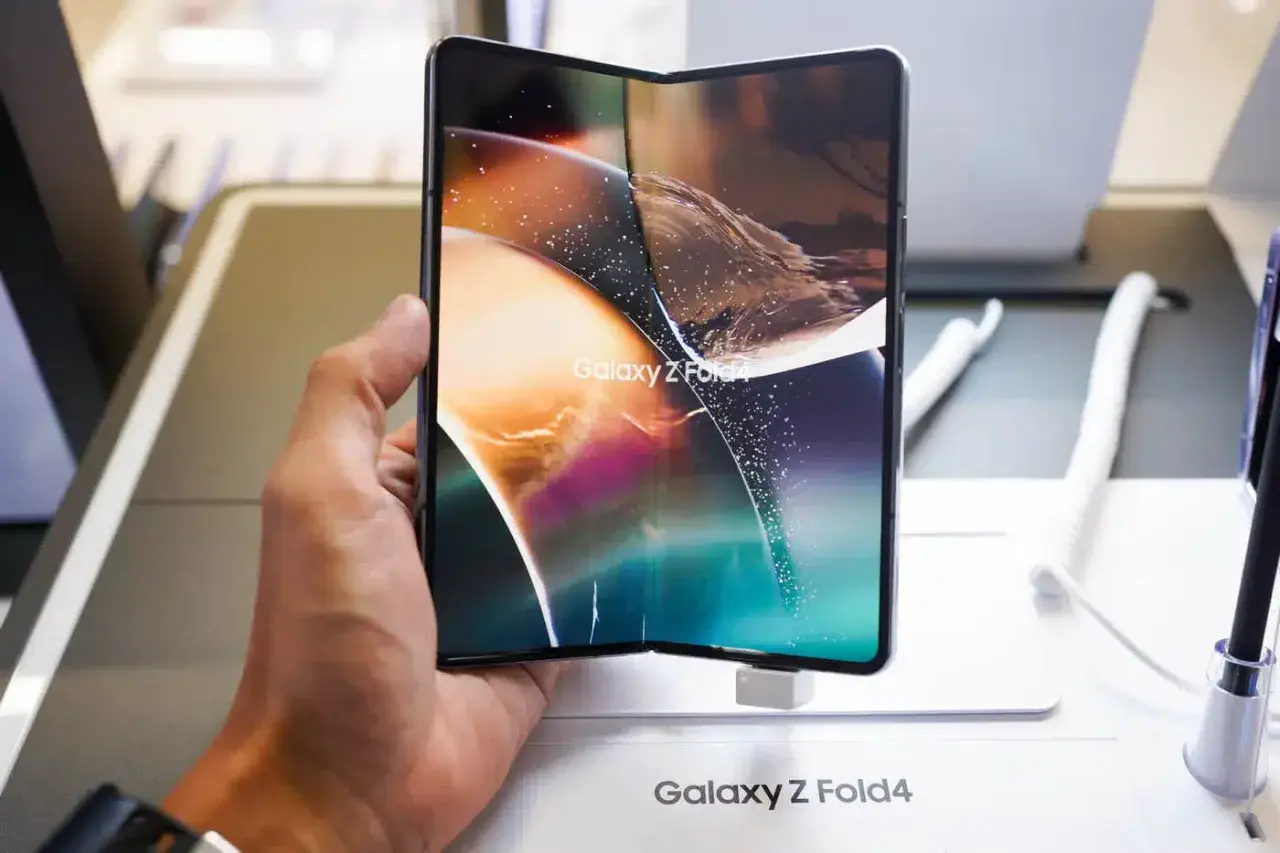 Dłoń trzyma rozłożony smartfon Galaxy Z Fold4, jeden z największych smartfonów na rynku, z kolorową tapetą.