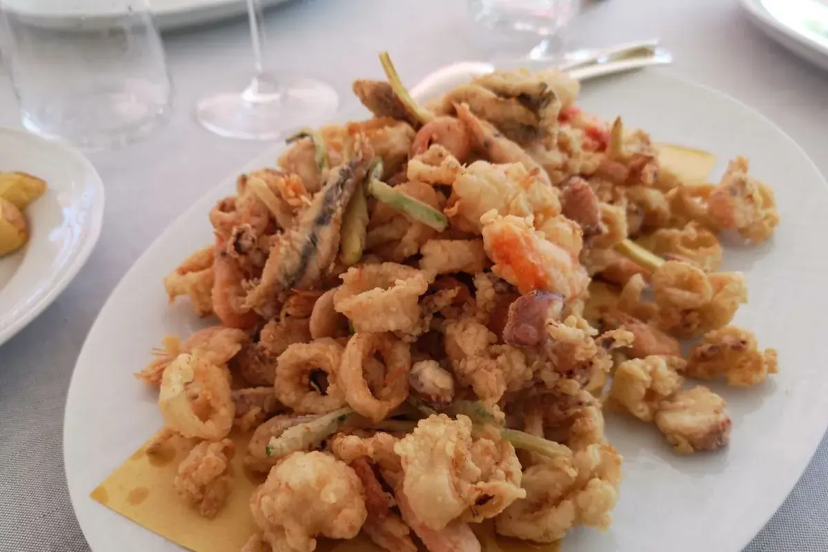 Un piatto invitante di frittura di paranza, con calamari, gamberi e pesciolini dorati e croccanti.